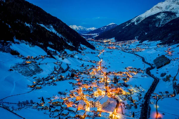 Paysage urbain nocturne d'hiver dans la ville autrichienne de Neustift. Vue aérienne du centre-ville et de l'église. Illumination nocturne des maisons et des feux de circulation. Tyrol, vallée de Stubai — Photo