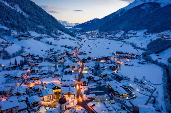 Paysage urbain du matin d'hiver dans la ville autrichienne de Neustift. Vue aérienne du centre-ville et de l'église. Éclairage matinal des maisons et des feux de circulation. Tyrol, vallée de Stubai — Photo
