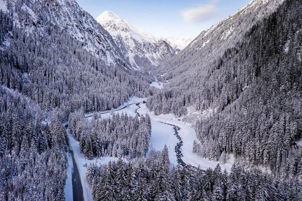 在空中俯瞰着雪地的森林，有高高的松树，还有冬天有车的道路。 Stubaital，Tirol，奥地利 — 图库照片