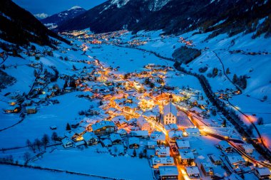 Avusturya 'nın Neustift kasabasında kış gecesi manzarası. Şehir merkezinin ve kilisenin havadan görüntüsü. Evlerin ve trafik ışıklarının gece aydınlanması. Tyrol, Stubai Vadisi