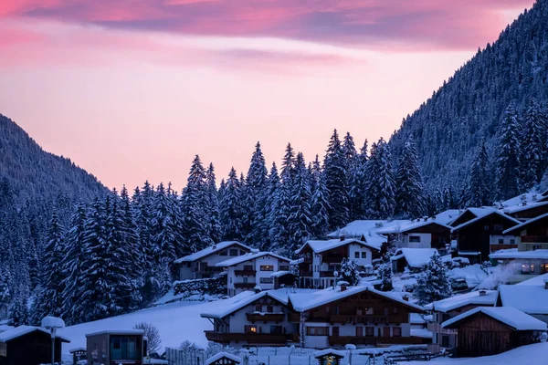 Tipik bir Avusturyalı köyü kış sabahı gün doğumunda. Karlı Orman Ağaçları ve Tirol Evleri