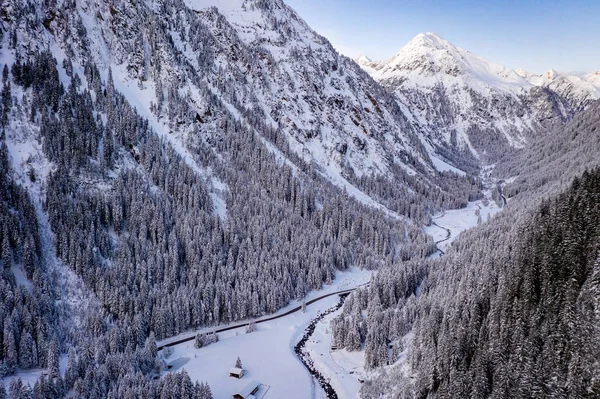 在空中俯瞰着雪地的森林，有高高的松树，还有冬天有车的道路。 Stubaital，Tirol，奥地利 — 图库照片