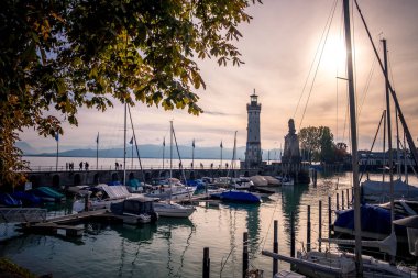 Lindau, Bodensee, Deniz feneri ve tekneler gün batımında rıhtımda.