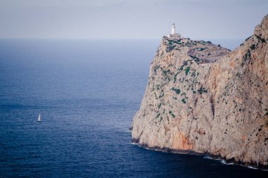 Cap de Formentor 'da deniz feneri ve denizde küçük bir yat. Mallorca Adası, İspanya
