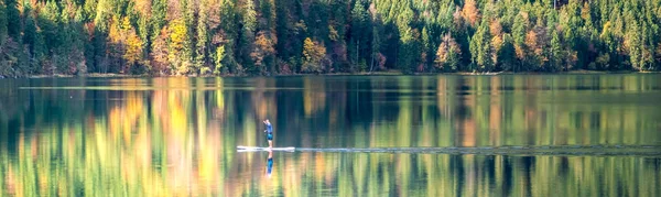A man floats on a board along the lake Eibsee at the Bavarian Garmisch Region — Stock Photo, Image