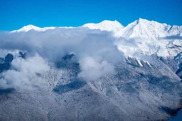 Paysage de montagne d'hiver à la station de ski Rosa Khutor à Sotchi, Russie. Arbres en gelée blanche contre un beau ciel matinal par un matin givré. Des canons à neige saupoudrent de neige sur les pentes — Photo