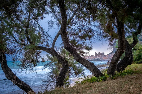 Seafront of Tyrrhenian Sea. View of the Sicilian city of Cefalu through trees growing on the shore — Stock Photo, Image