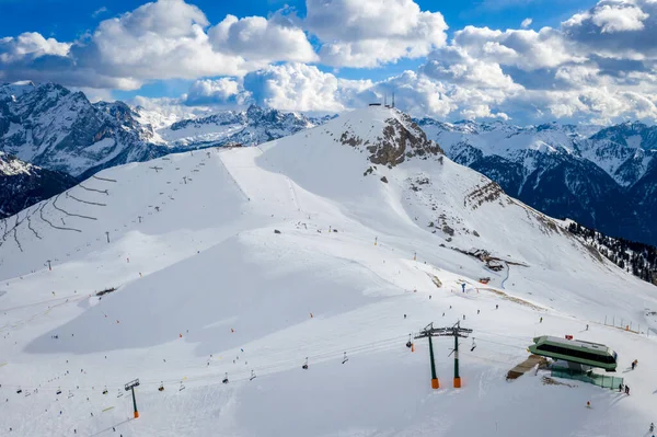 Krajobraz w ośrodku narciarskim Campitello di Fassa Włochy. Dolomity zimowe i błękitne niebo z chmurami. Widok z lotu ptaka na stok narciarski i wyciągi narciarskie — Zdjęcie stockowe