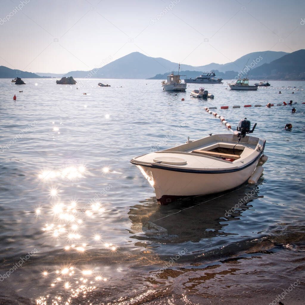 View of the fishing boat in the Przhno beach in Montenegro at sunset. The suns rays are beautifully reflected from the water