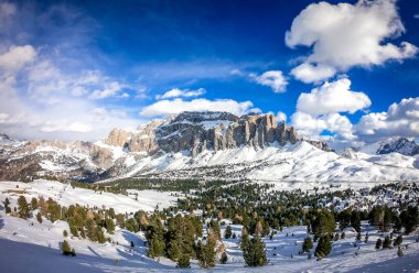 Campitello di Fassa İtalya 'da bir kayak merkezinin manzarası. Kış Dolomitleri ve bulutlu mavi gökyüzü.