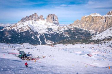 View of a ski resort piste with people skiing in Dolomites in Italy. Ski area Belvedere. Canazei, Italy clipart