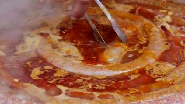 Cuisine à la saucisse de porc dans une casserole et poignardage au couteau, préparation traditionnelle des aliments 