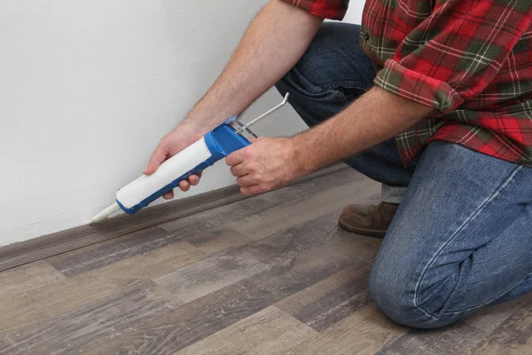Home renovation, worker caulking batten with silicone — Stock Photo, Image