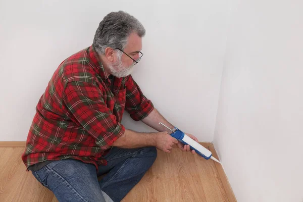 Home renovation, worker caulking batten with silicone — Stock Photo, Image