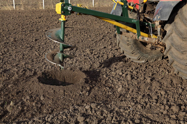 Drilling holes in field, preparing for trees planting