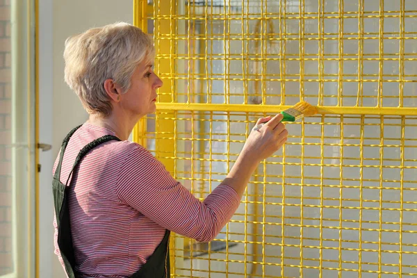 Worker painting metal protective net to yellow color — Stock Photo, Image