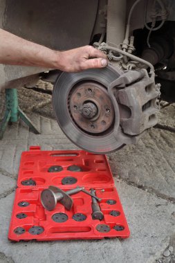 Araba tamircisi bir arabanın disk frenleriyle çalışır.