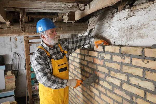 Worker building brick wall in old barn — Stock Photo, Image