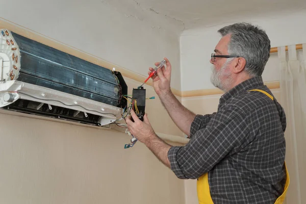 使用螺丝刀维修房间内空调装置的电工 — 图库照片