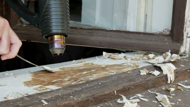 ヴィンテージウィンドウの復元 木材から古い塗料を削除するにはパテナイフと電気ヒートガンを使用して労働者 — ストック動画