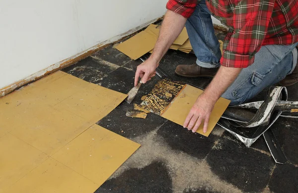 用刮胡刀把旧的乙烯瓷砖从厨房地板上移开 — 图库照片