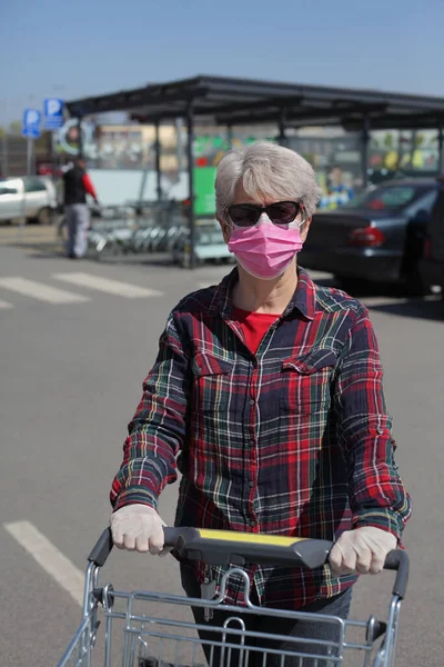 Women with protective gloves and mask pushing shopping carts, corona virus basic protection