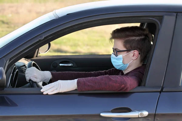 若いです10代のドライバー保護外科マスクと手袋車の中で座って コロナウイルス保護者 — ストック写真
