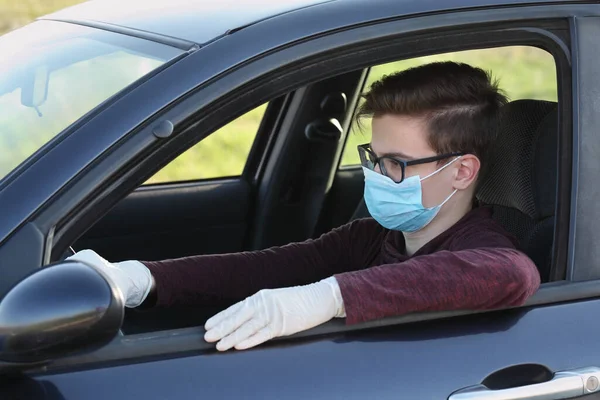 若いです10代のドライバー保護外科マスクと手袋車の中で座って コロナウイルス保護者 — ストック写真