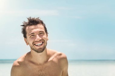 Gök mavisi deniz zemininde kameraya gülümseyen genç adamın portresi.