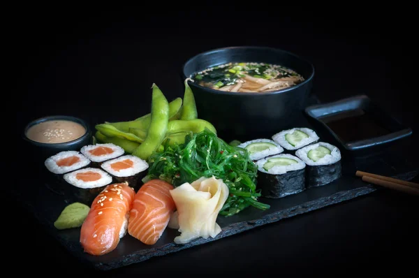 健康的日本本顿午餐 搭配鲑鱼面 黄瓜面 黑鱼寿司 海藻色拉 芝麻面和黑背景的味豆腐汤 — 图库照片