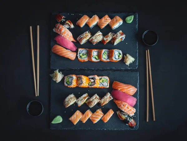 Nigiri suşisi, Uruamaki California, Philadelphia, Unagi taştan tabakta yuvarlanıyor. Üst görünüm, siyah arkaplan. 
