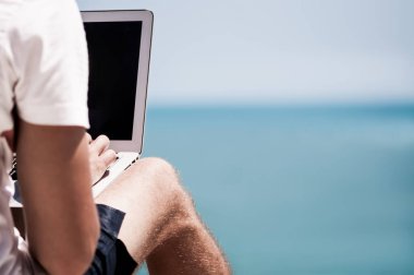 Genç adam Tayland Körfezi 'ne bakan yüksek kıyı uçurumunda uzaktan çalışıyor..