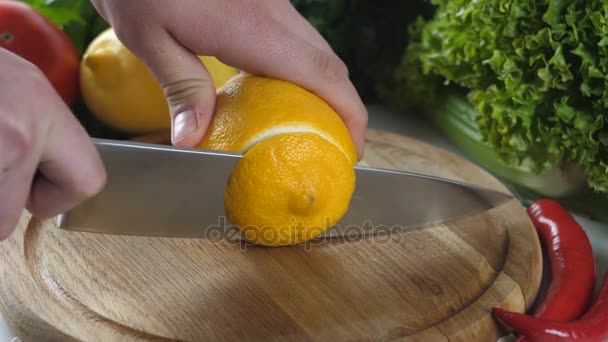 Mans hands cutting a lemon on a piece — Stock Video