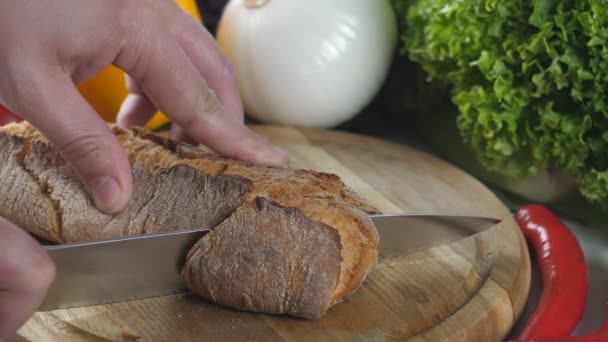 Mens hands cut bread and lay a knife on the table — Stock Video