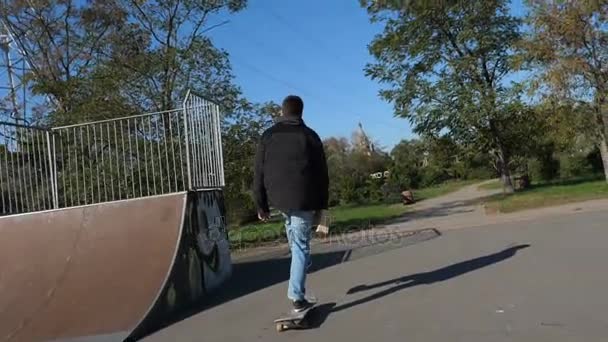 Passeios de skate no skate com uma caixa na mão, vista lateral traseira . — Vídeo de Stock