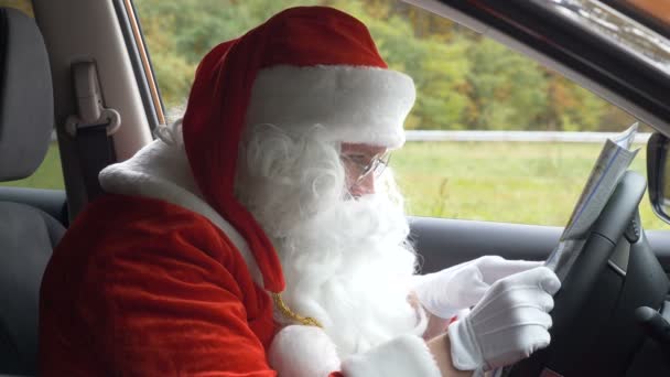 Санта-Клаус заблудился и смотрит на карту в машине со скоростью 50 кадров в секунду — стоковое видео