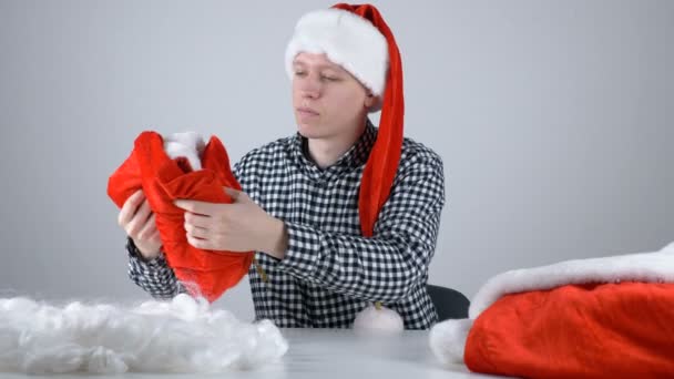 Mladý muž v klobouku Santas se dívá na Santa Claus kalhoty 50 fps — Stock video