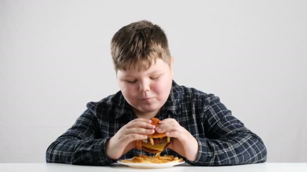 Vet jongen eet een grote hamburger 50 fps — Stockvideo