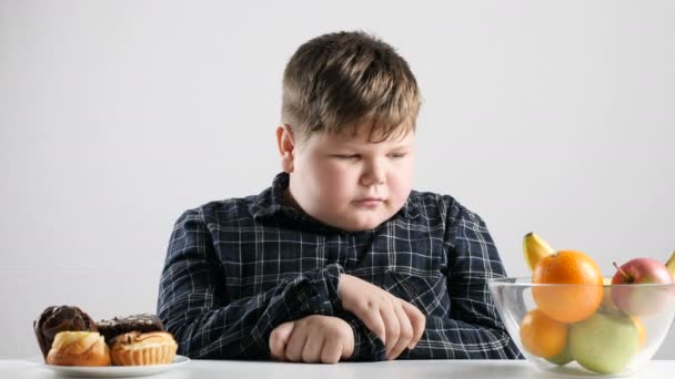 Joven niño gordo elige pasteles en lugar de frutas 50 fps — Vídeo de stock