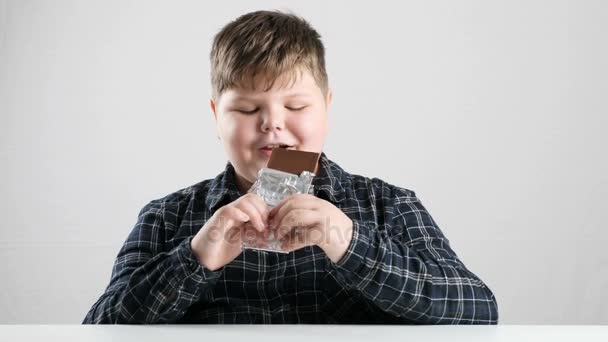 Jovem gordo menino leva mordida de chocolate bar 50 fps — Vídeo de Stock