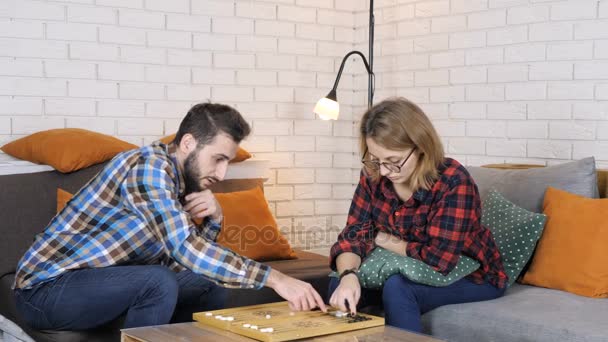 Кавказский человек учит девушку, как играть в нарды 50 кадров в секунду — стоковое видео