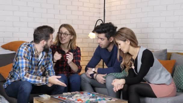 Nadnárodní společnost, která sedí na gauči a hrát desková hra monopoly, mluvit, diskutovat o 50 fps — Stock video