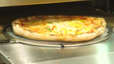 Otomatik fırın, peynir erime ve aşçı dışarı hareket pizza alır.