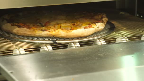 Pizza moving out of the automatic oven, cheese melting. — Stock Video