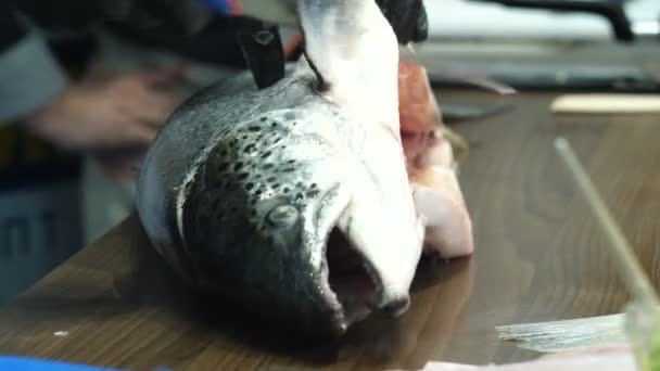 Le mani di uomini in guanti neri tagliano la testa di un pesce — Video Stock