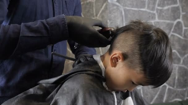 Peluquero con guantes negros afeita al niño asiático detrás de la cabeza 60 fps — Vídeo de stock