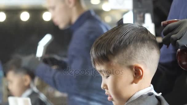 Peluquero en guantes negros rociando y peinando el cabello de un niño asiático 60 fps — Vídeos de Stock
