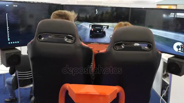 KYIV, UCRANIA - 21 DE OCTUBRE DE 2017 Dos adolescentes están jugando un simulador de carreras . — Vídeo de stock
