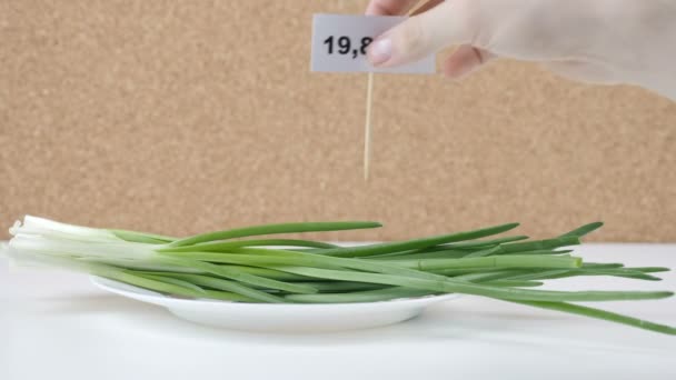 Cantidad de calorías en cebolla verde, mano masculina pone un plato con el número de calorías en una cebolla verde — Vídeo de stock