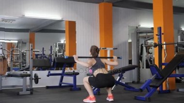 Genç güzel sportif kız geri bir spor spor salonunda bir çizgiyle çömelme yan görüntülemek 60 fps